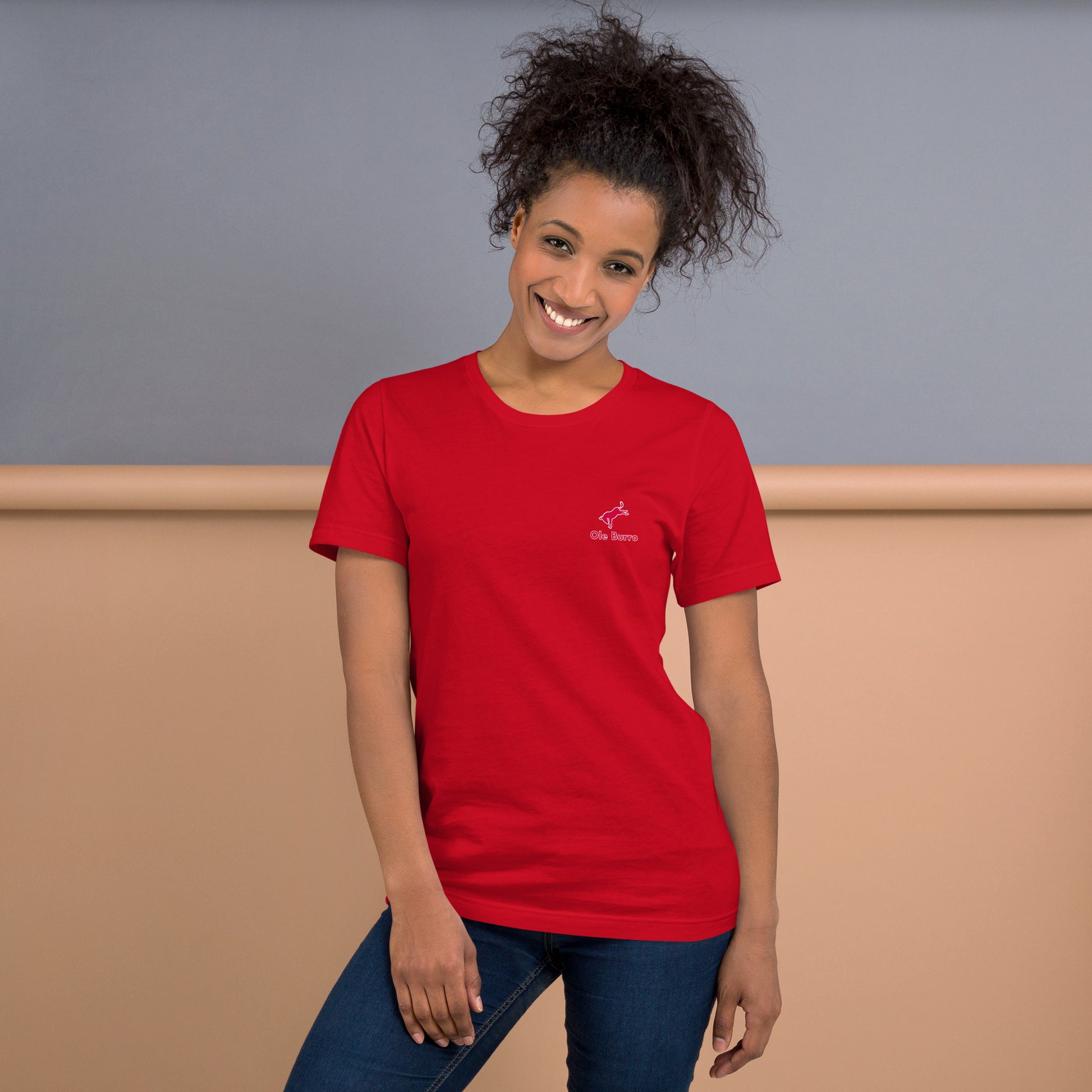 Woman wearing a red t-shirt with a logo against a neutral background