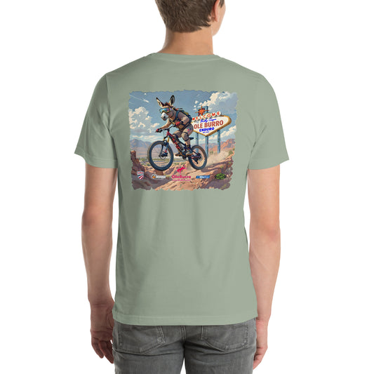 Person wearing a light green t-shirt with a graphic of a  burro on a mountain bike on the back. and a sign in the desert.