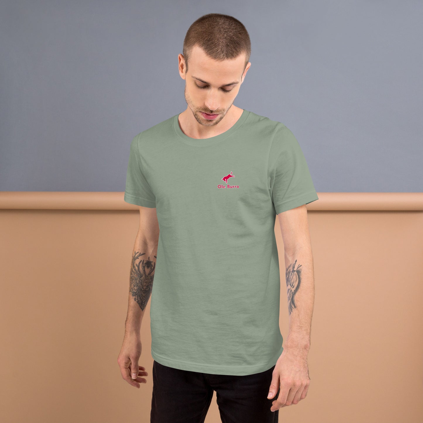 Man wearing a green t-shirt with a small logo on a plain background