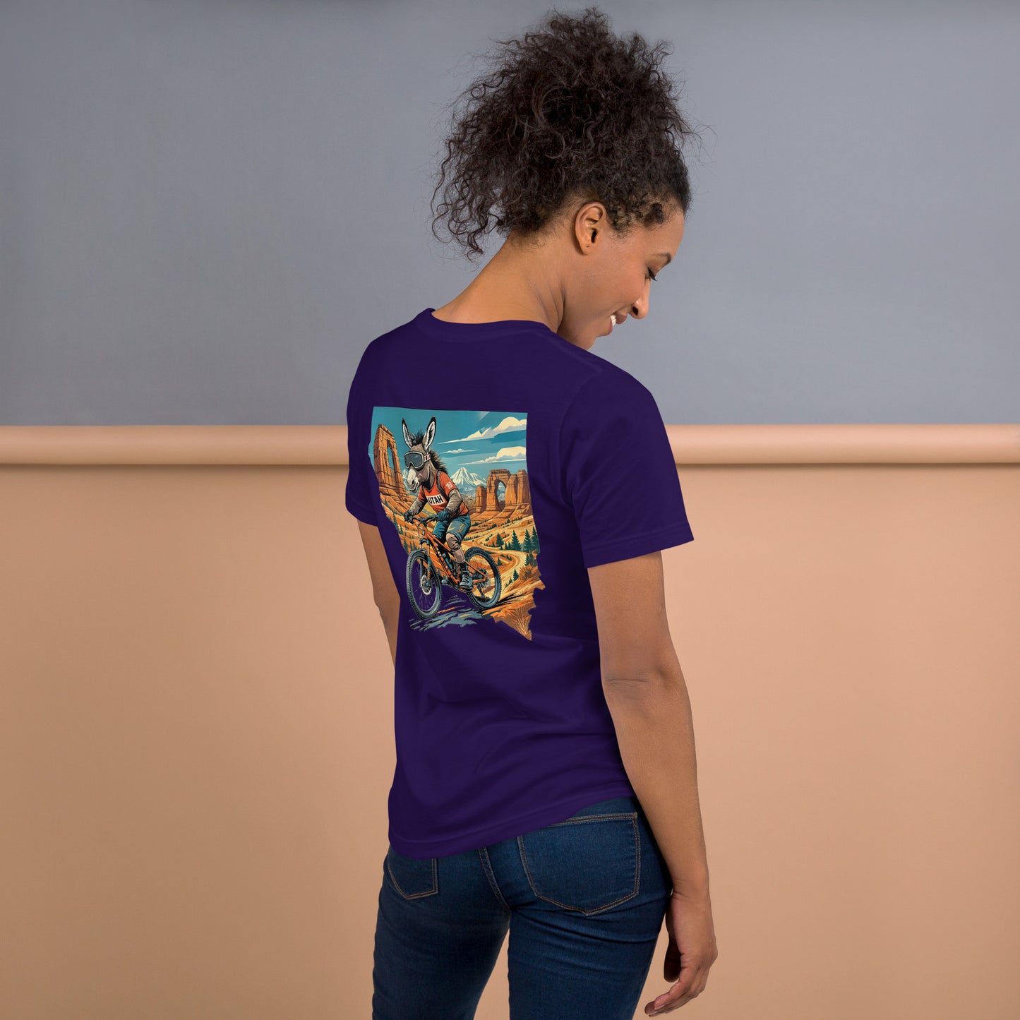 Person wearing a purple t-shirt with a colorful graphic on the back, standing against a neutral background.