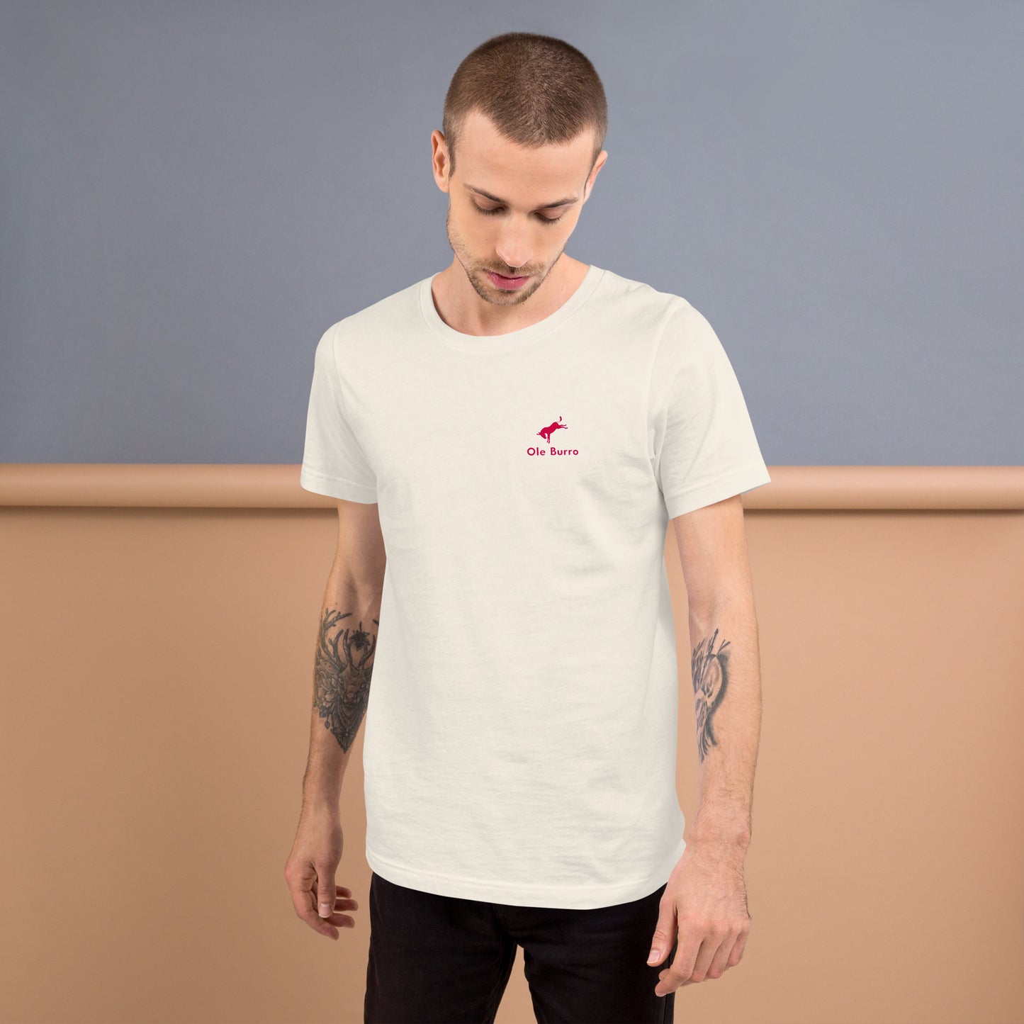 Man wearing a white t-shirt with a small logo on a plain background