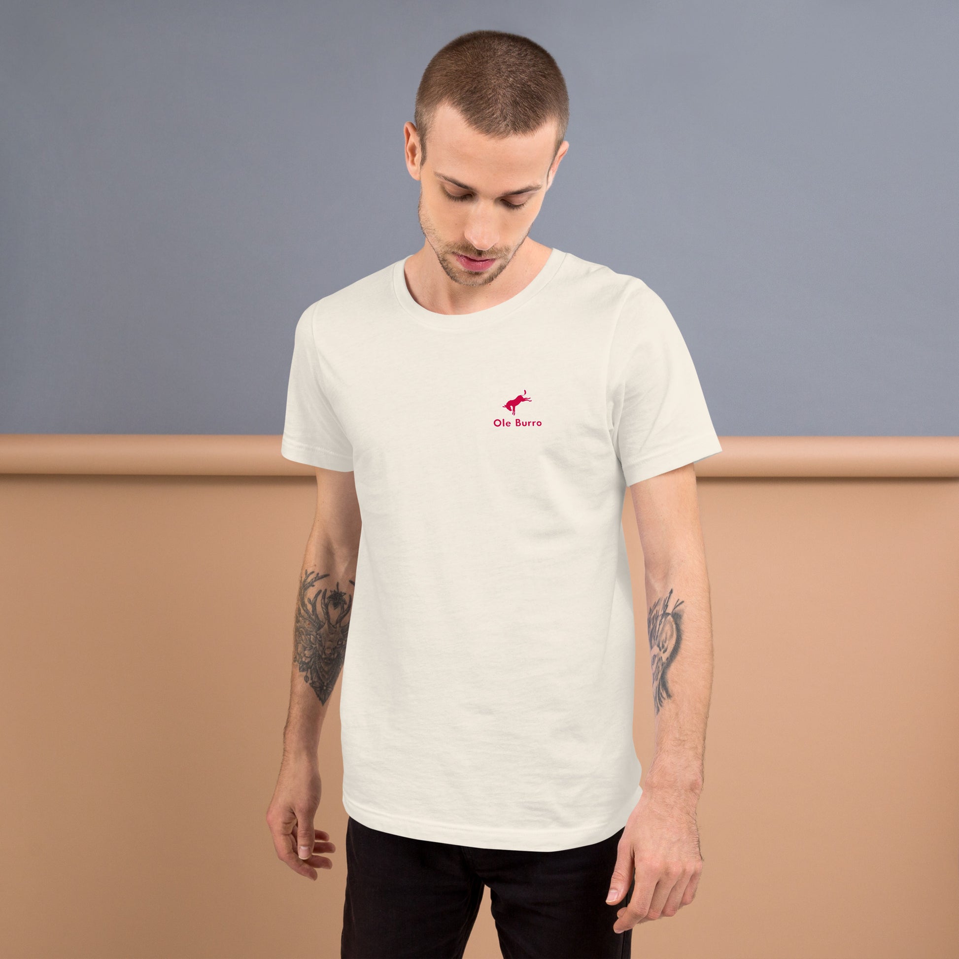 Man wearing a white t-shirt with a small logo on a plain background
